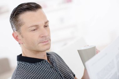 smart man sat holding cup and reading newspaper clipart