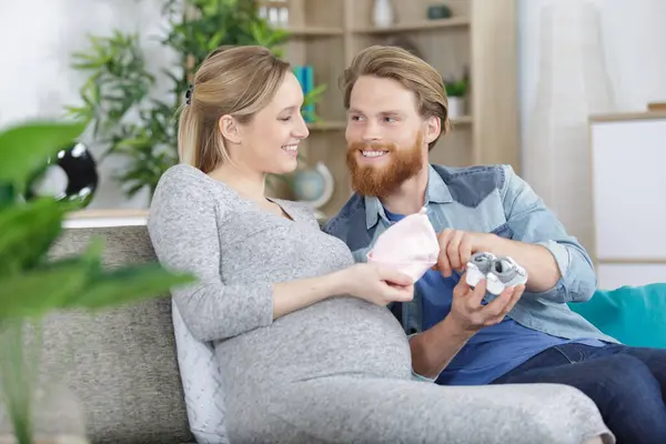 Pregnant Couple Sitting Sofa Baby Cloths Belly — Stock Photo, Image