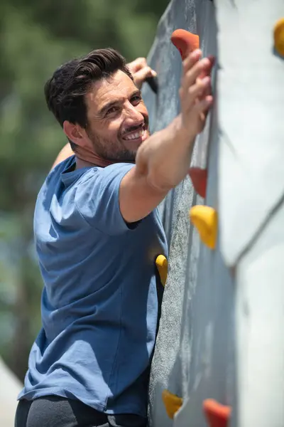 happy man climber on artificial climbing wall