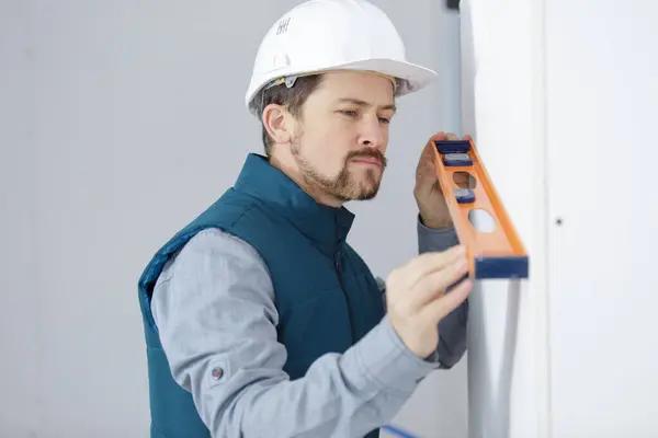 Young Homeowner Using Spirit Level Wall Stock Photo