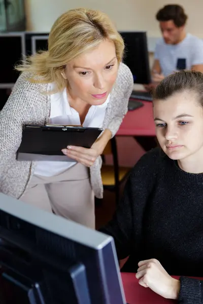 Teacher Helping Young Female Student Using Computer 图库图片