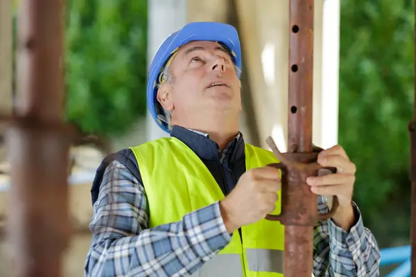 建筑工人站在建筑工地用管子 免版税图库图片