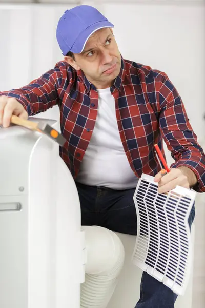 Male Technician Repairing Air Conditioner Stock Photo