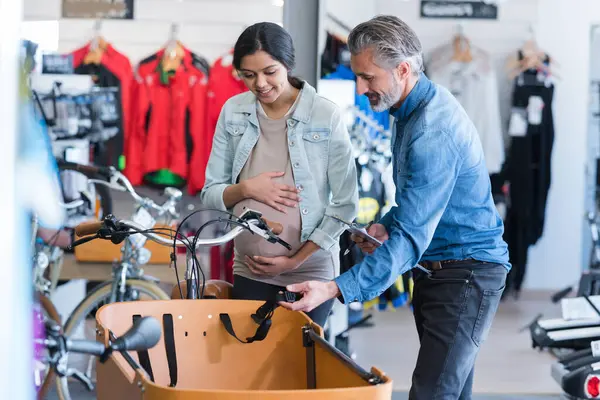 怀孕妇女在自行车店服务 免版税图库图片
