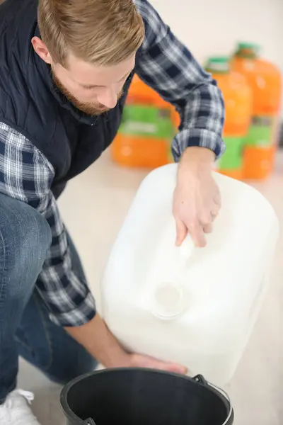 Uomo Versando Liquido Detergente Secchio Foto Stock