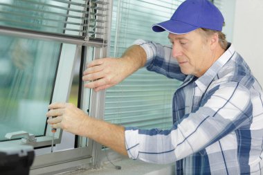 man installing a new blind on a window clipart