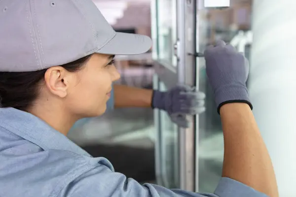 stock image young woman unscrews the fixing screws of the window handle