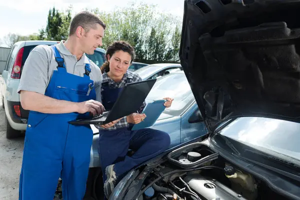 stock image female mechanic working on car engine with colleague