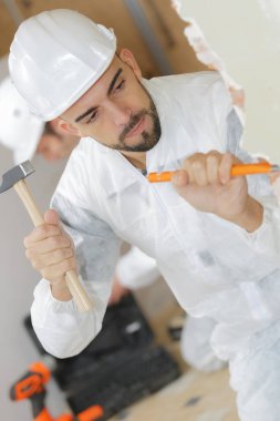 young man contactor with a chisel and hammer clipart