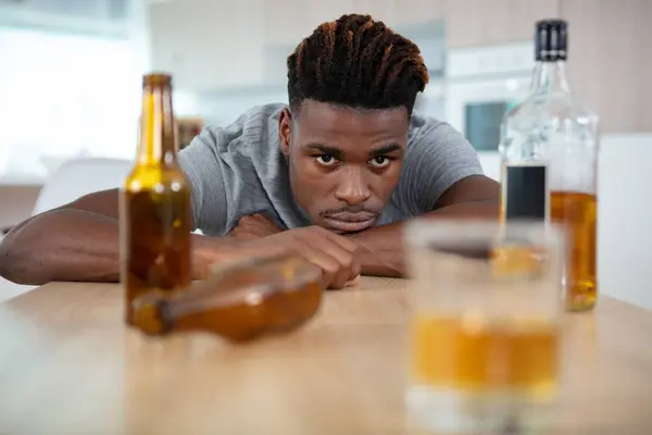 stock image man staring across table at glass of alcohol