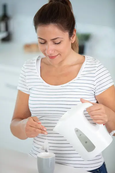 stock image woman pours water off electric kettle