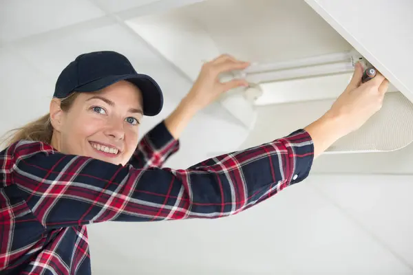 stock image a woman changing light bulb