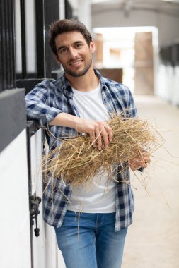 portrait of cheerful man standing at a stable clipart