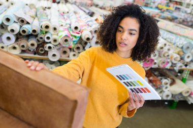 woman inspecting a good fabric material for furniture clipart