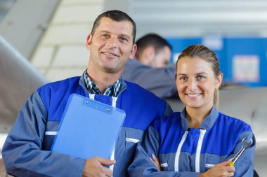 mechanics in hangar repairing light aircraft clipart