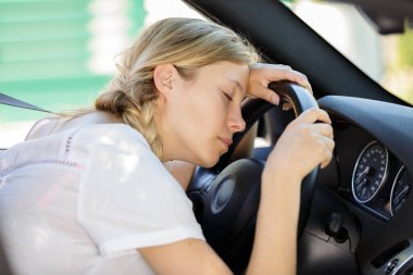 young woman asleep slumped over the wheel of her car clipart