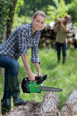 woman in the forest using a chainsaw clipart