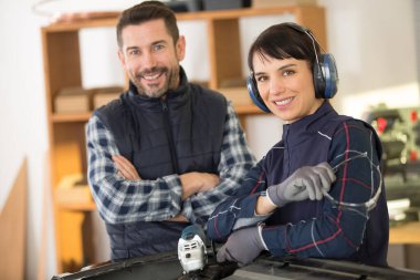 man with woman using angle grinder on car bodywork clipart