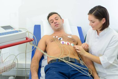 Nurse sticking heart monitor pads onto patient clipart