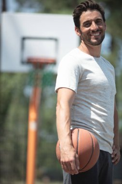 handsome smiling man carrying a basketball ball clipart