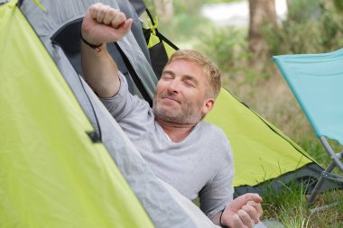 man relaxes during camping holiday clipart