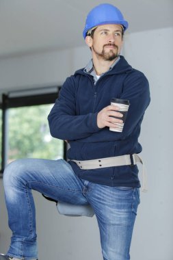 worker holding cup of coffee indoors clipart