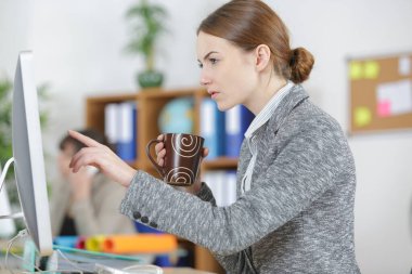 businesswoman holding coffee cup and pointing at computer screen clipart