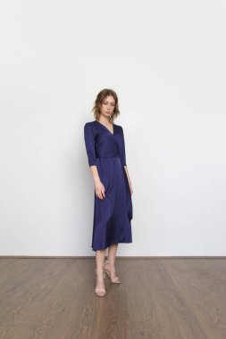 Stüdyo fotoğrafları. Koyu mavi ipek saten Midi elbisesi içinde genç bir kadın model..