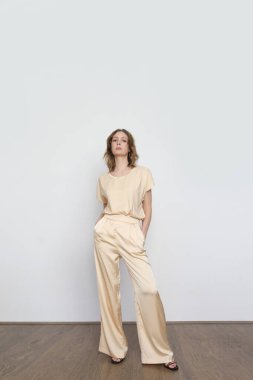 Stüdyo fotoğrafları, bej renkli ipek elbiseli genç bir kadın model.. 