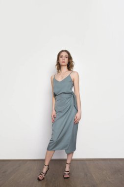 Mavimsi gri gecelikli ipek bluz ve sarılı midi etek giyen bir kadın model. Tek renkli yaz kostümü çok şık. Moda Stüdyosu çekimi.