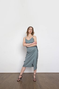 Mavimsi gri gecelikli ipek bluz ve sarılı midi etek giyen bir kadın model. Tek renkli yaz kostümü çok şık. Moda Stüdyosu çekimi.