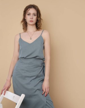 Mavimsi gri gecelikli ipek bluz ve sarılı midi etek giyen bir kadın model. Tek renkli yaz kostümü çok şık. Moda Stüdyosu çekimi.