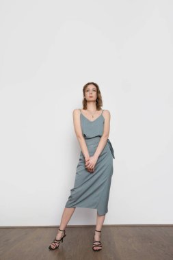 Mavimsi gri gecelikli ipek bluz ve sarılı midi etek giyen bir kadın model. Tek renkli yaz kostümü çok şık. Moda Stüdyosu çekimi.
