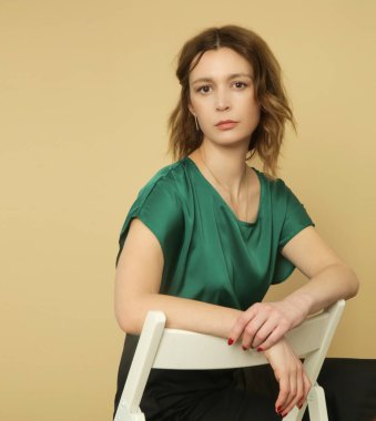 Stüdyo fotoğrafları. Yeşil bluz ve siyah etek giyen genç bir kadın model.