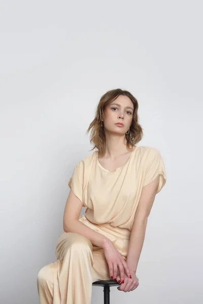 セリエのスタジオ写真の若い女性モデルでベージュシルク衣装 — ストック写真