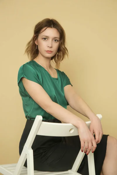 穿着绿色衬衫和黑色裙子的年轻女模特的演播室照片系列 — 图库照片