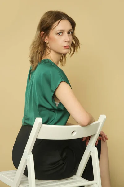 穿着绿色衬衫和黑色裙子的年轻女模特的演播室照片系列 — 图库照片