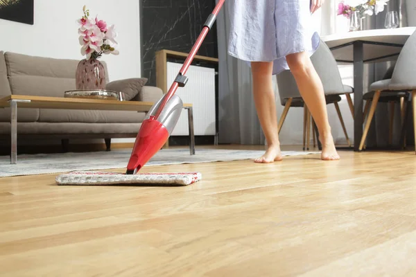 Woman cleaning floor in the living room with mop