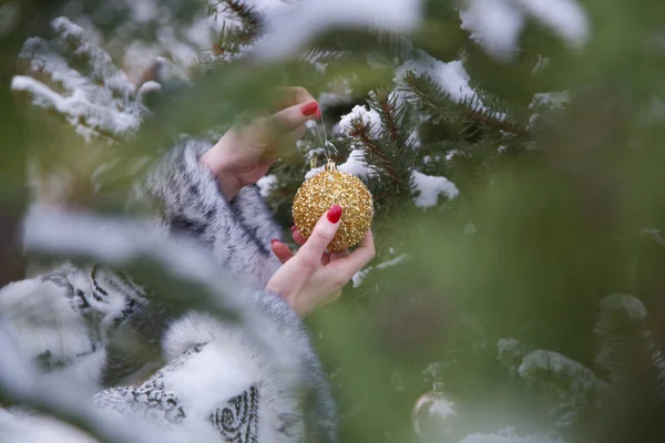 一个女人用金色的圣诞泡沫装饰户外圣诞树 假日和冬季概念 — 图库照片