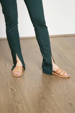 Çam yeşili dar pantolon ve yarık pantolon giyen kadın model. Stüdyo çekimi.