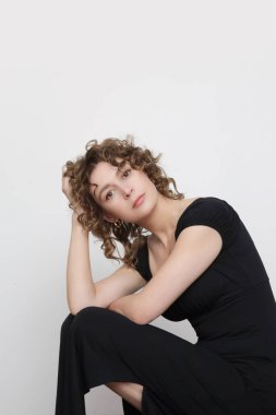 Uzun elastik siyah klasik ve çok yönlü bir elbise giyen genç kadın modelin seri fotoğrafları. 