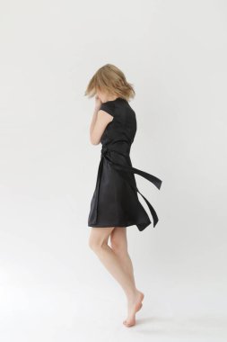 Stüdyo fotoğraflarının serisi. Siyah ipek saten elbise giymiş genç bir kadın model..