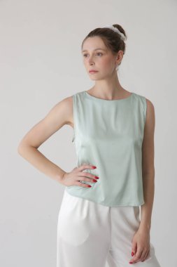 Nane yeşili ipek kolsuz bluz giyen kadın modelin stüdyo fotoğrafı.