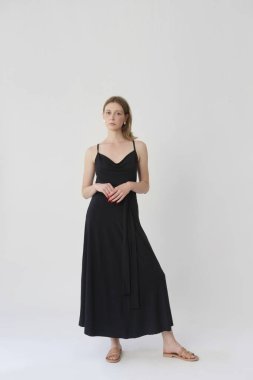 Stüdyoda çekilen, rahat ama şık pamuklu siyah elbiseli genç bir modelin fotoğrafları.