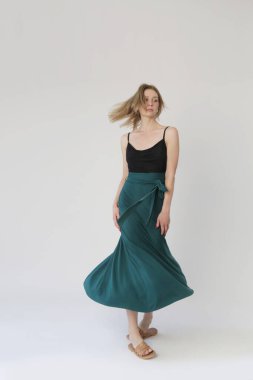 Serie of studio photos of young female model in comfortable yet stylish cotton outfit, black shit and emerald green skirt.