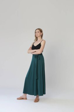 Serie of studio photos of young female model in comfortable yet stylish cotton outfit, black shit and emerald green skirt.