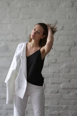 Studio photos of young female model in black and white smart casual outfit - blazer, blouse and jeans