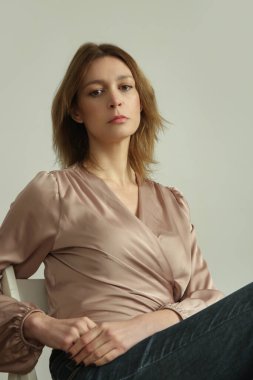 Serie of studio photos of young female model wearing beige silk satin wrap blouse