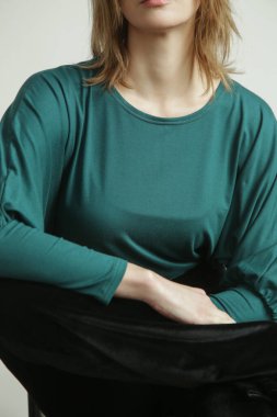 Studio photo of young female model wearing green long sleeved shirt made from organic cotton. Comfortable sustainable fashion.