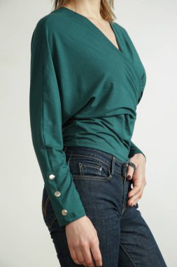 Studio photo of young female model wearing skinny jeans and green shirt made from organic cotton